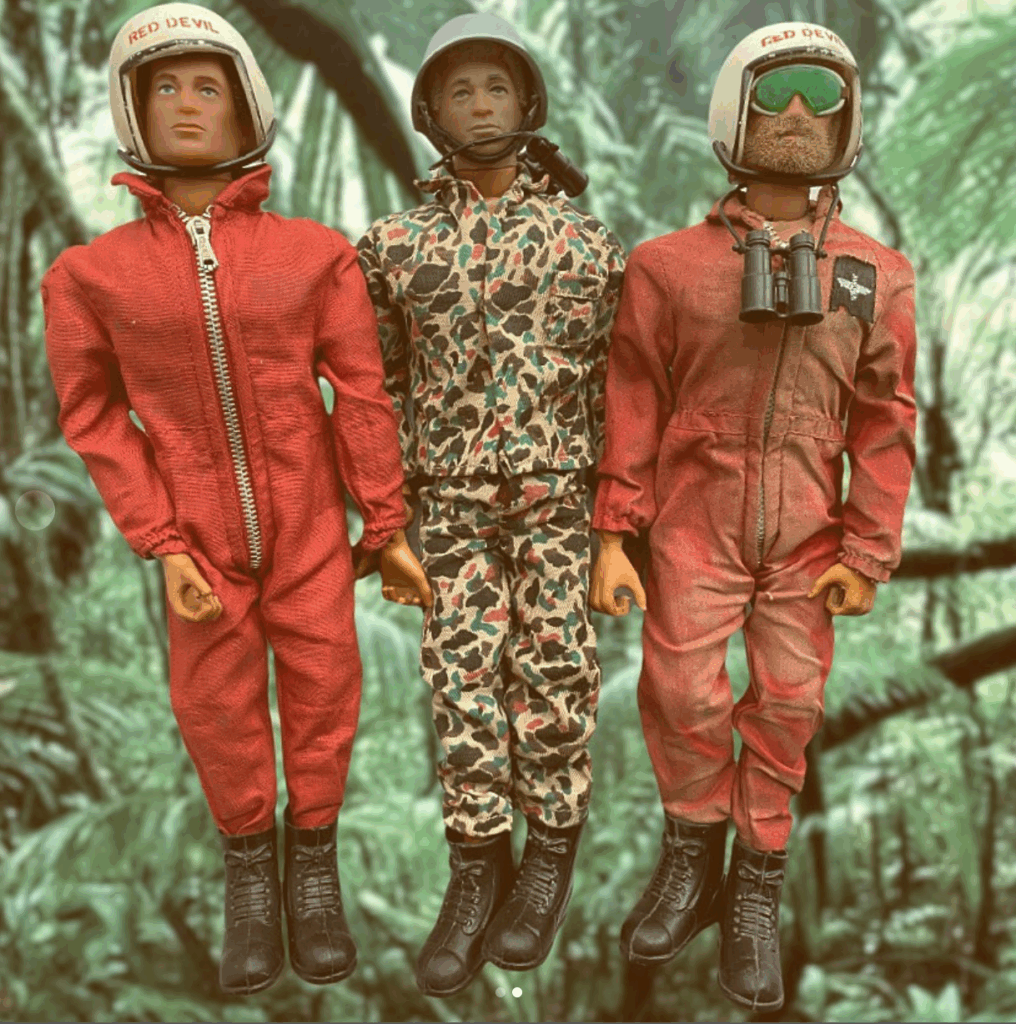 Tres figuras Action Man con monos rojos y camuflaje, cascos Red Devil y fondo selvático.